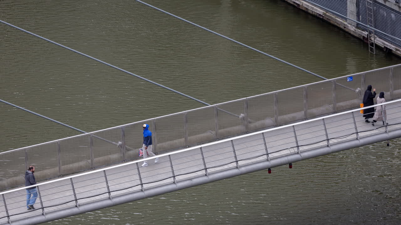 사람들이 강을 가로지르는 다리를 가로질러 고 있다