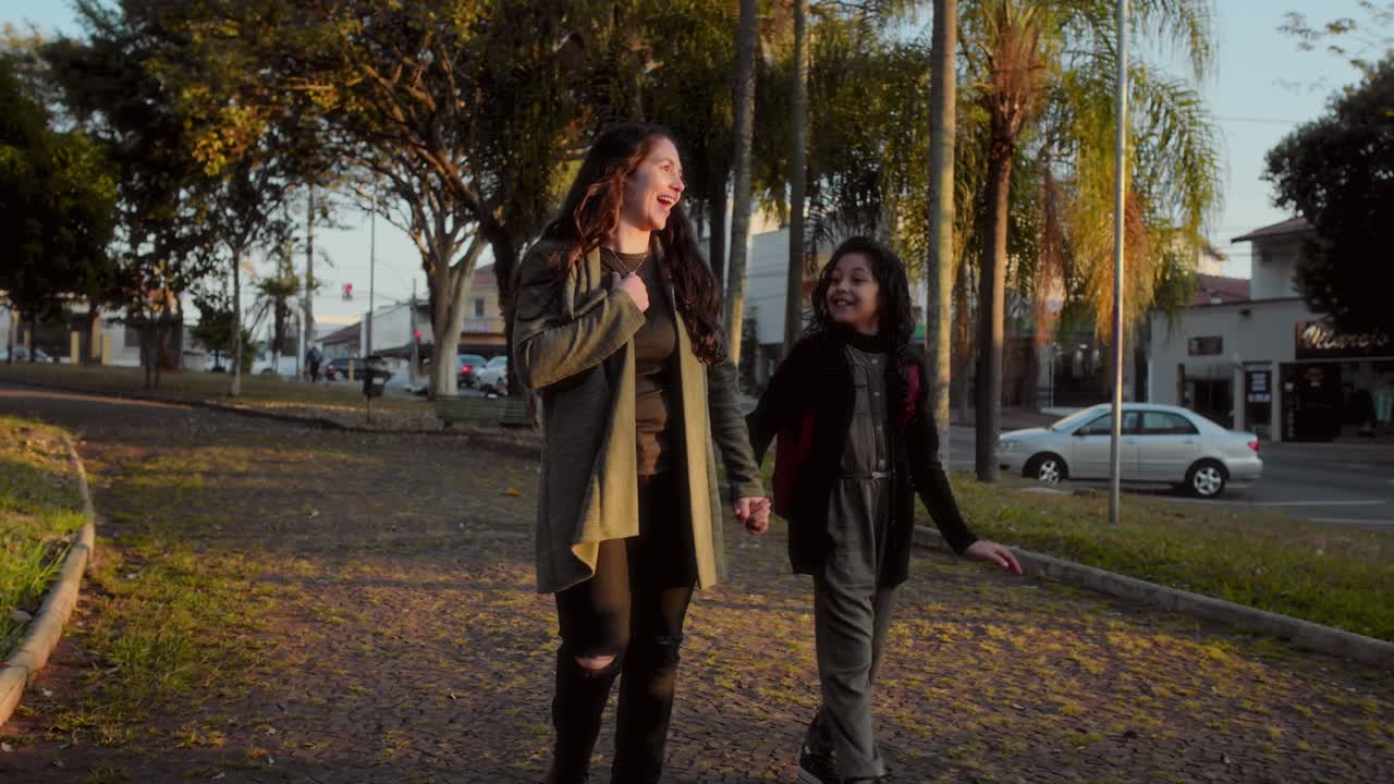 Madre e Figlia che Camminano Mano nella Mano in un Parco all'Ora d'Oro