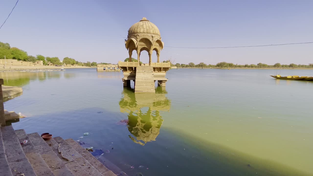 Gadsisar Lake in Jaisalmer glistens under the Rajasthan sun, reflecting ancient temples and serene pavilions. Golden light, calm waters, and migratory birds enrich its timeless desert charm