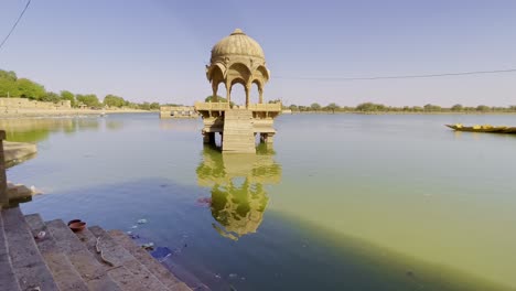 gadsisar lake in jaisalmer glistens under the rajasthan sun, reflecting ancient temples and serene pavilions. golden light, calm waters, and migratory birds enrich its timeless desert charm