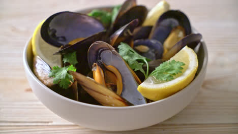 fresh mussels with herbs in a bowl with lemon