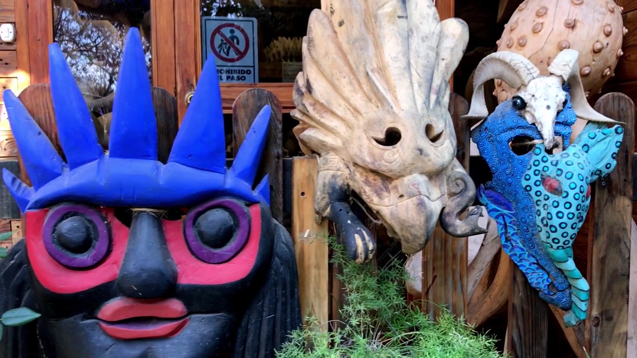 Närbild av färgglada handgjorda djurmasker utställda utanför en hantverksverkstad som visar upp traditionellt hantverk och dekorativ folkkonst under dagtid i Mexiko.