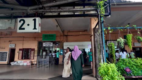 kandy railway station showing locals on the platform. people are moving through the station, showcasing daily life in sri lanka with greenery and traditional architecture in the backdrop.