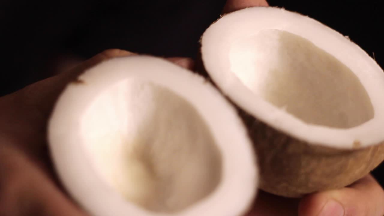 Close-up of Hands Holding Open Coconut Halves