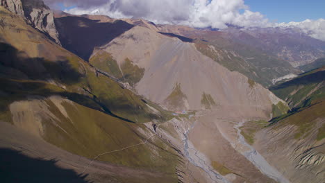 Drone-shot-Tilicho-Base-Camp-trekking-trail-landscape,-Annapurna-Manang-Nepal,-clouds-and-sunny-weather-4K