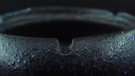 a macro close up shot of ash residue from a cigarette in a black stone ashtray, slow motion 4k video, white smoke 3