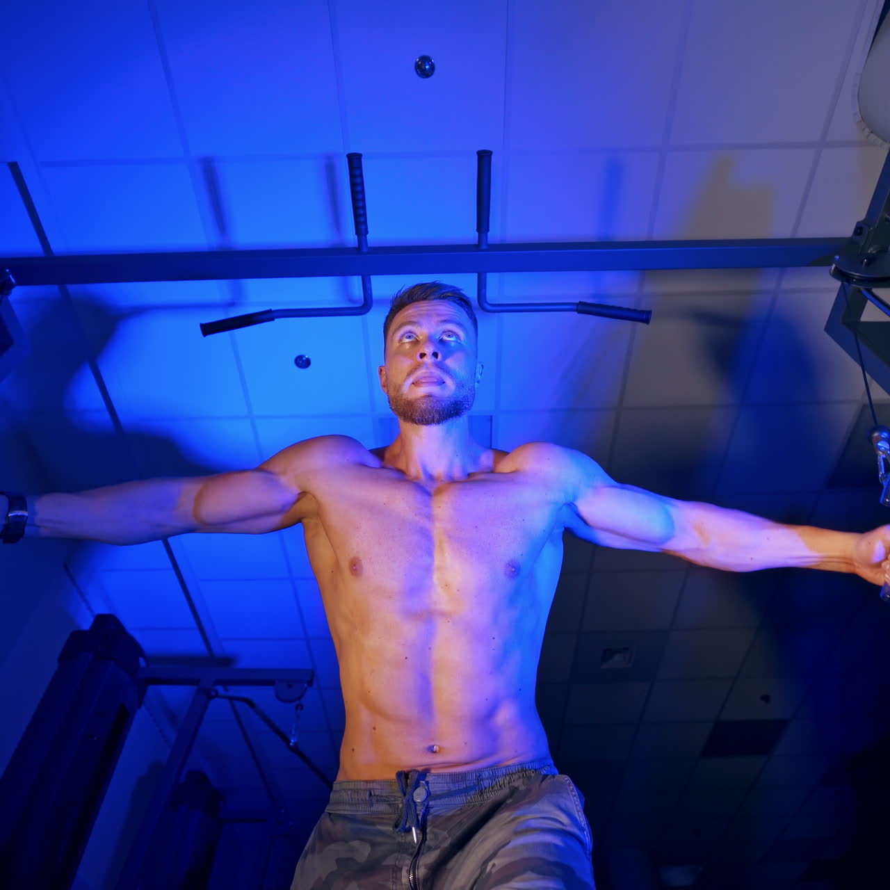 Athlete with strong body doing work out pushing up excercise in gym. View from the bottom.