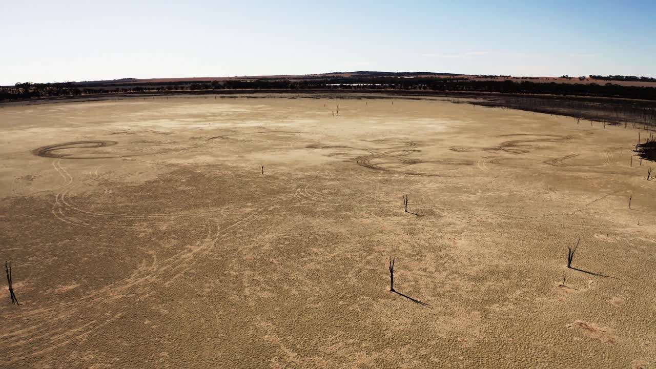 Drone circling shot of isoltate dead trees on a wide, dry salt lake in Western Australia