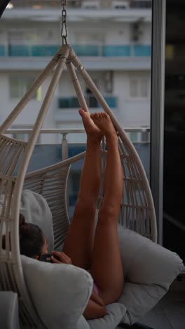 woman relaxing in a hanging chair on a balcony