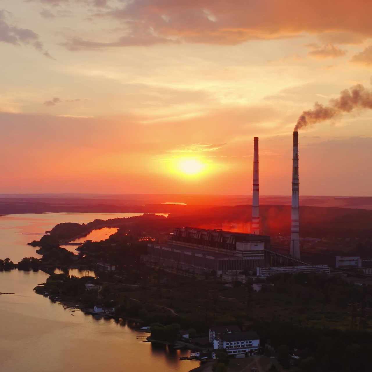 Factory chimneys with smoke. Beautiful sunset over river. View from the top