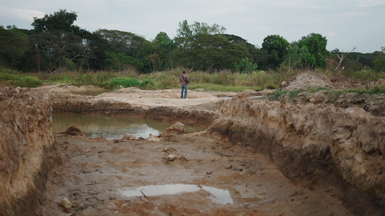Homem em pé perto de um lago em uma área de construção