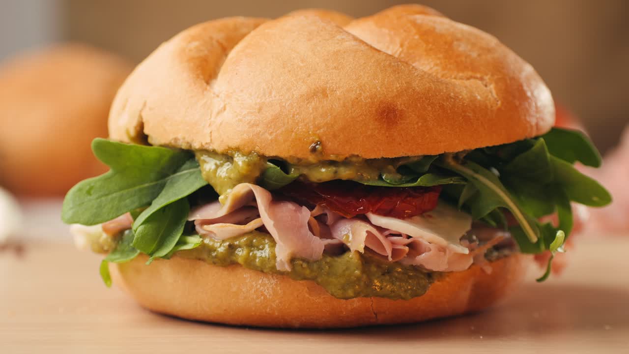 Mortadella ham sandwich, Traditional italian focaccia filled with thin pesto slices of mortadella, served by chef man in cafe restaurant. Macro of traditional italian spanish tapas antipasti.