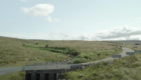 wicklow, ireland - a car driving along a narrow road winding through the heart of a green landscape - drone flying forward