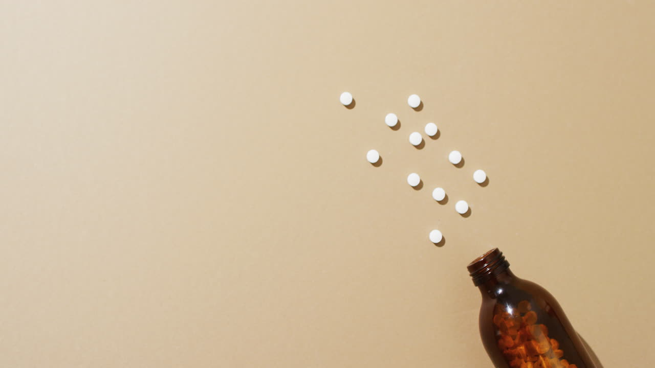video de una botella marrón derramando píldoras blancas sobre un fondo marrón con espacio para copiar