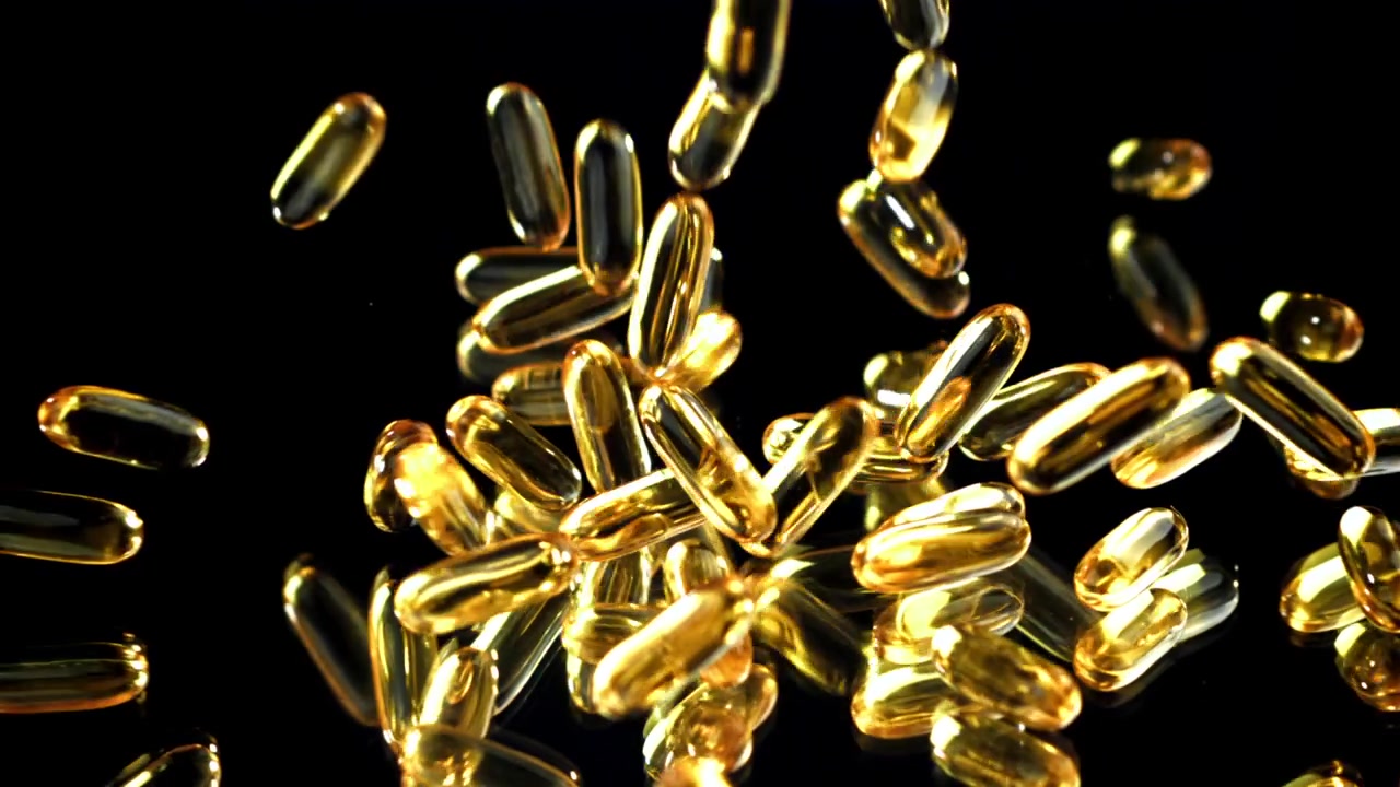 Caduta di capsule dorate su una superficie riflettente nera