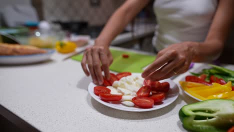 mujer preparando una comida con tomates, queso y verduras