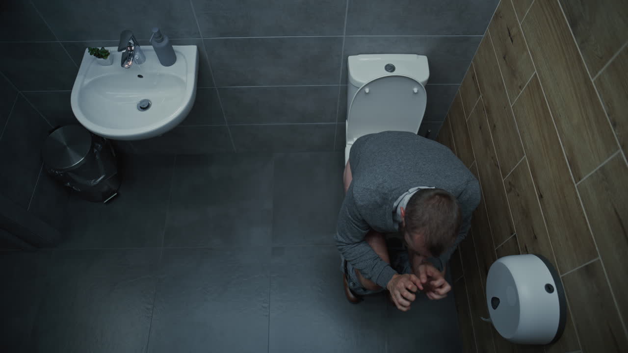 Man Taking Off Pants Sitting on Toilet Experiencing Diarrhea and Digestive Discomfort