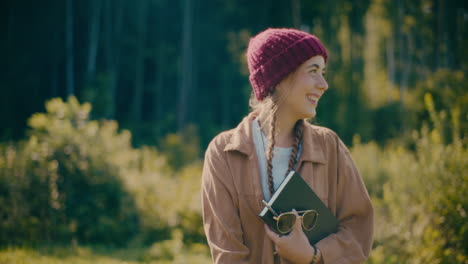 Mujer-Feliz-Sosteniendo-Un-Diario-Y-Caminando-En-El-Bosque