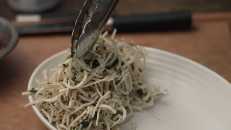 plating cooked healthy pasta with tongs. close up