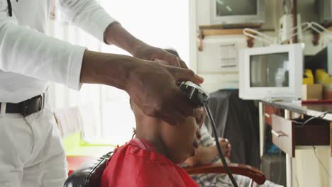 african man cutting african boy hair