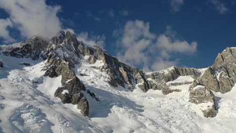 4K-drone-shot-flying-towards-massive-mountain-with-clouds-rolling-off-summit