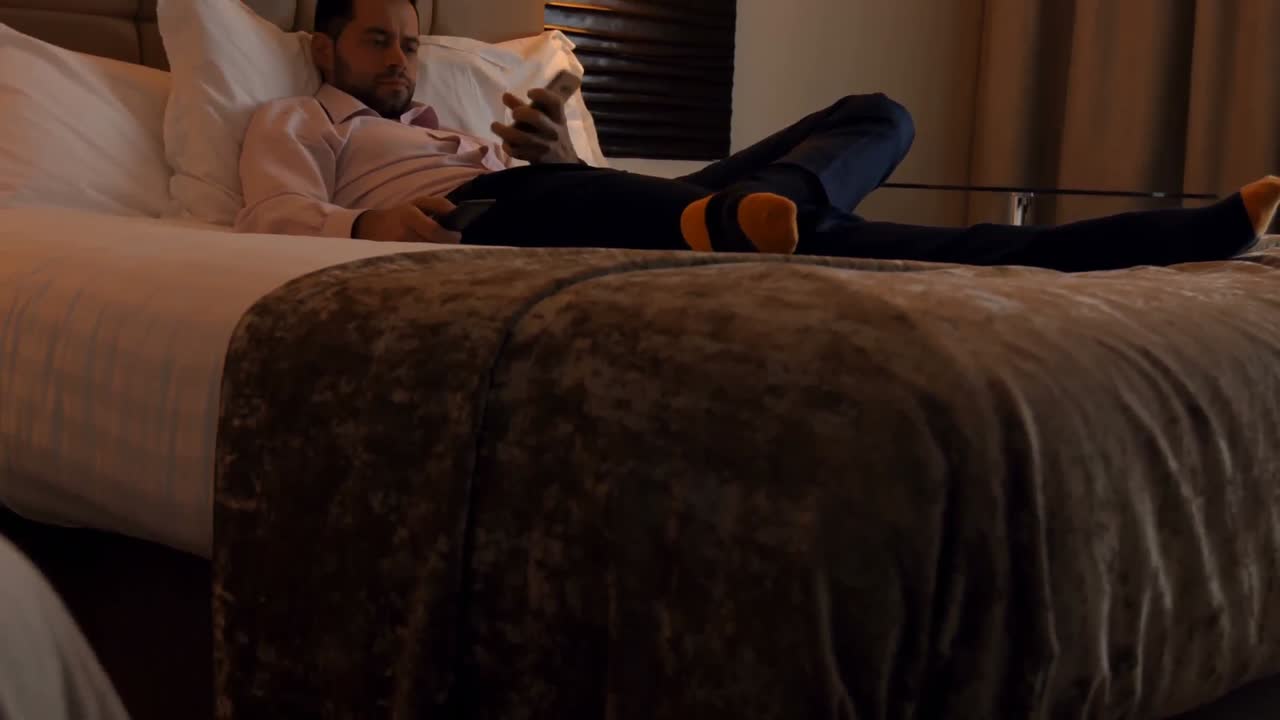 침실 4k에서 휴대 전화를 사용하는 사업가