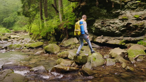 Un-Joven-Turista-Masculino-Cruza-Un-Río-De-Montaña-En-El-Bosque-Video-4k