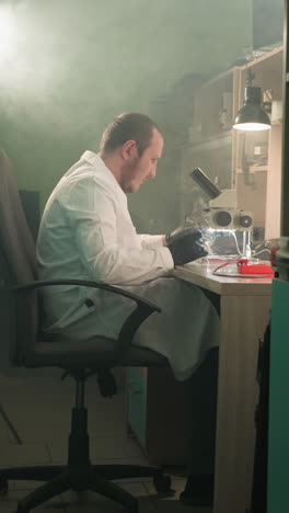 a middle view of a technician in a lab coat meticulously working on electronic components under a microscope in a well-equipped lab, the room is filled with tools in the shelf