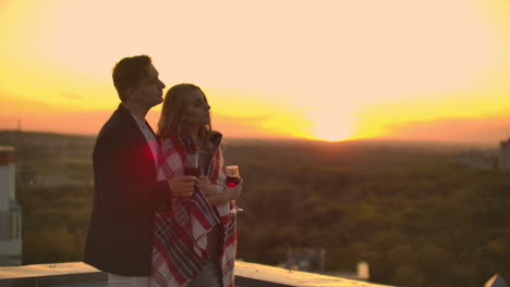 una pareja enamorada está sentada en el techo de la casa. en la distancia las luces de la ciudad nocturna.