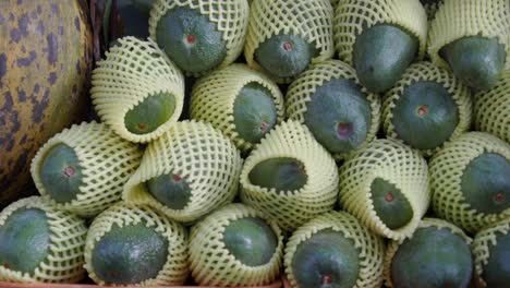 a pile of green avocados for sale at a market.