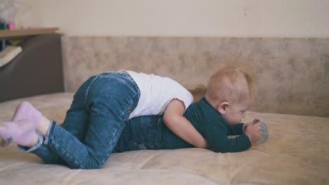 cute girl hugs funny brother with water bottle on large bed