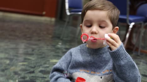 video of a child sitting on the floor and enjoying making soap bubbles with a toy and being surprised by it