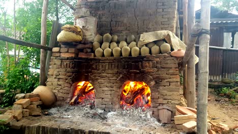 leña de primer plano se quema en el viejo horno las ollas de vajilla se secan en el estante