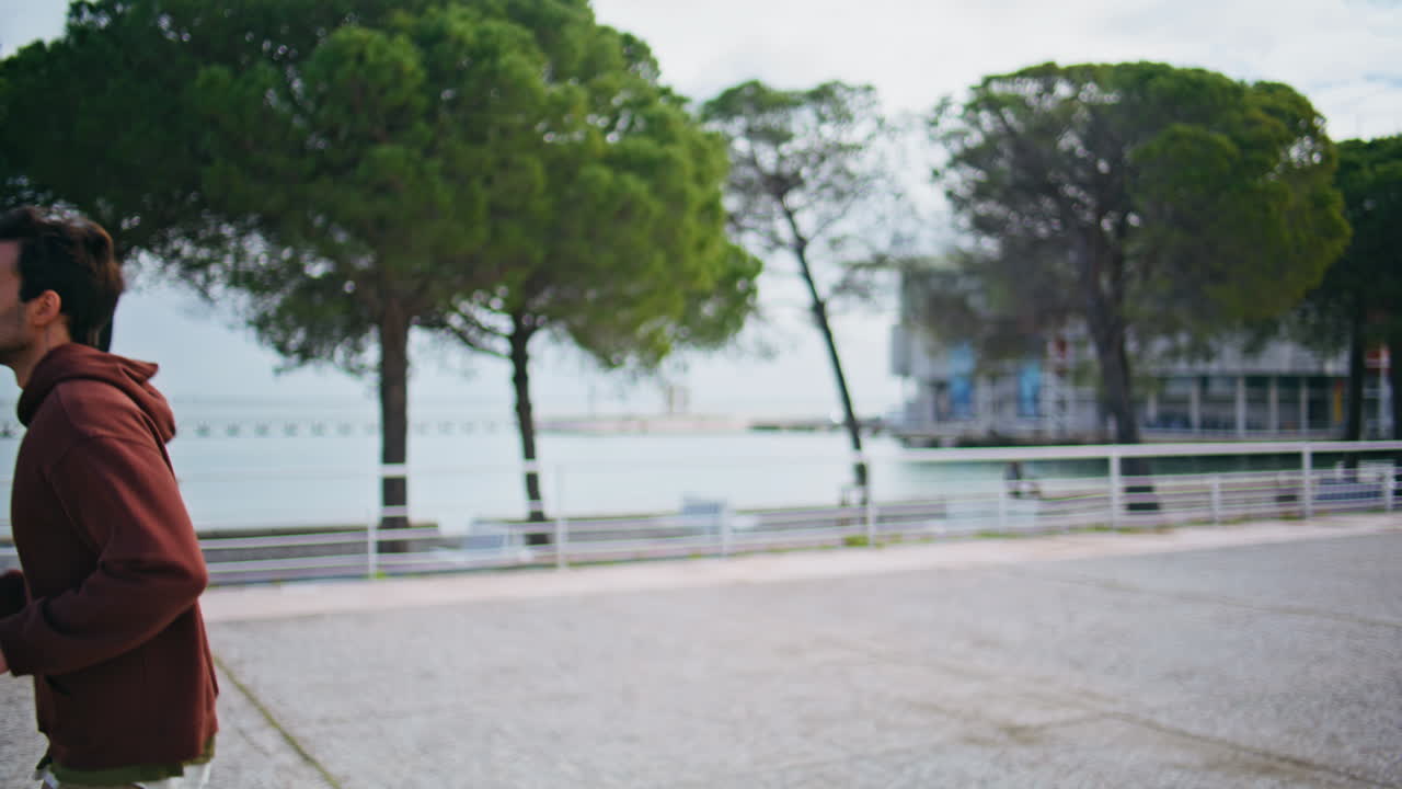 Motivated guy running outdoors in morning alone. Closeup jogger training river