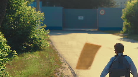 boy throws away paper sheets running to grey fence 2