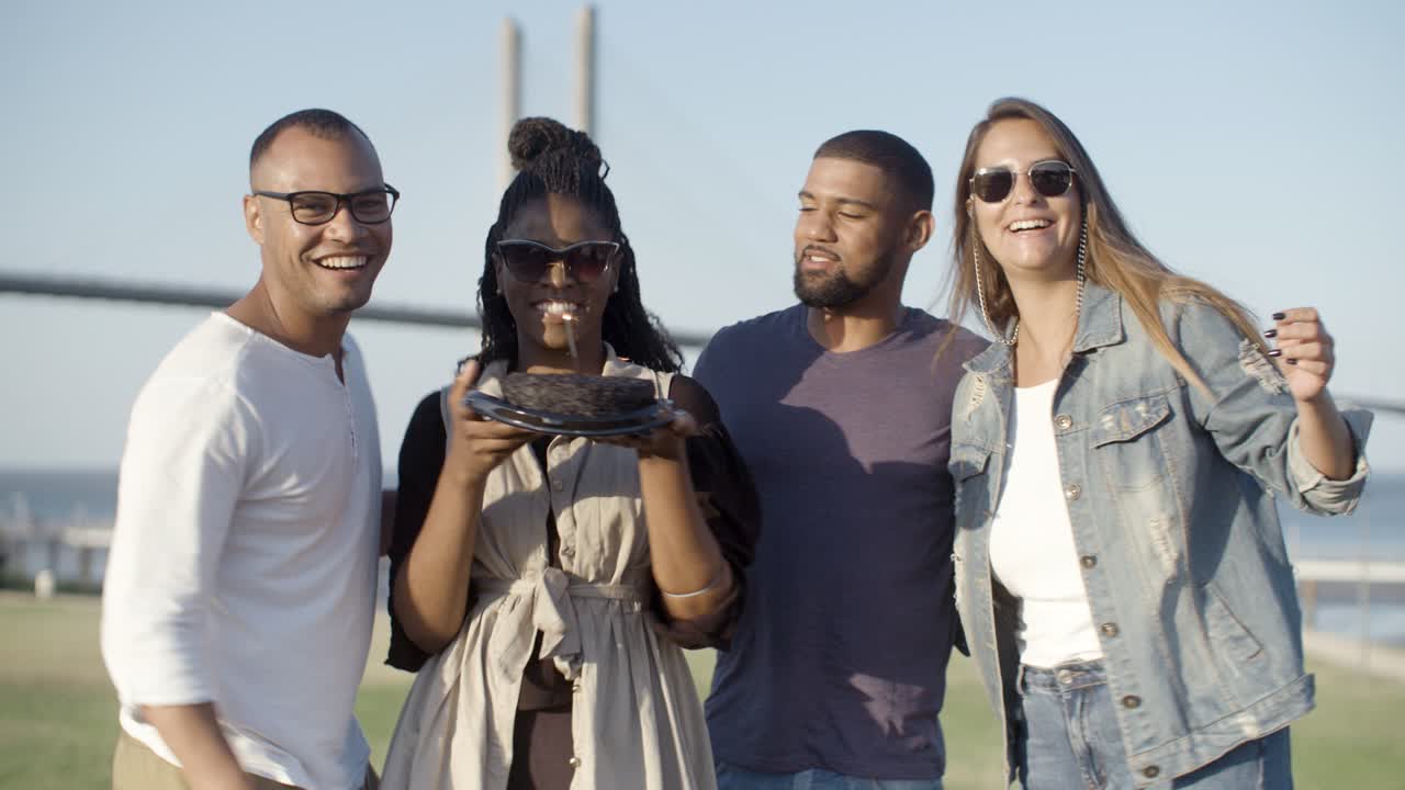 una mujer afroamericana sonriente sosteniendo un pastel con chispas