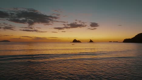 sunset sky reflecting on sea water with golden ripples in costa rica - drone shot