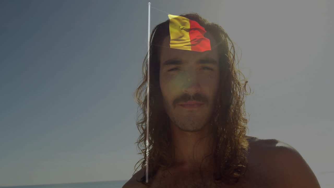 Står på stranden, man med långt hår bär liten flagga på huvudet