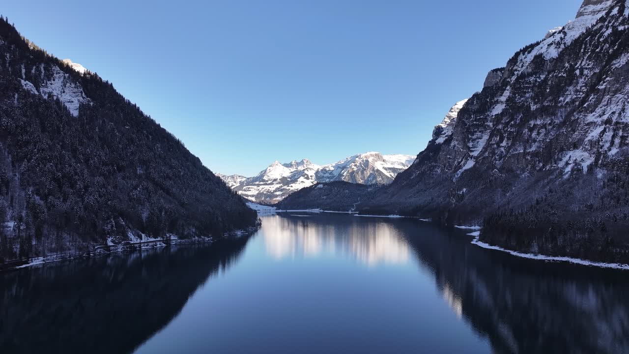 Aerial - Klöntalersee reflecting snowy Alps in Klöntal, Switzerland, peaceful winter scene