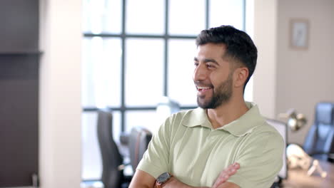 smiling man in office with arms crossed, enjoying conversation with colleagues