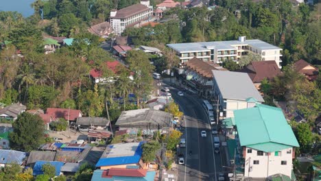 flyover drone shot of koh chang's white sand beach, thailand. sunny morning over the village, sea, and lush greenery