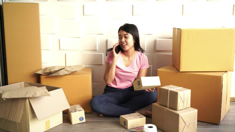 propietaria de una empresa asiática que trabaja en casa con una caja de embalaje en el lugar de trabajo