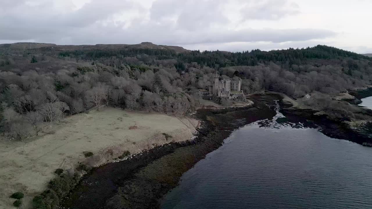 Dunvegan castle on the isle of skye, surrounded by woodland and the sea, under a cloudy sky, aerial view