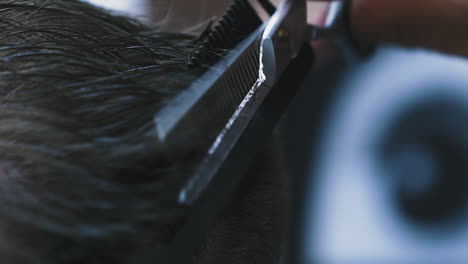 hairdresser does haircut to client using comb and scissors