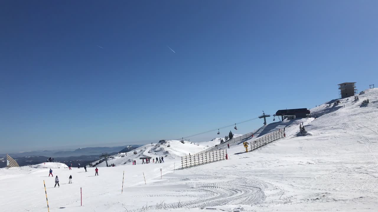 Scenic winter ski ambiance of skiers enjoying on flat groomed ski run on top of mountain  on sunny winter blue sky in 4k