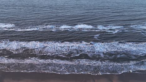 Aerial-view-Sea-waves-approaching-the-shore-break-on-the-beach,-and-so-little-by-little,-the-sand-is-washed-away-from-the-beach
