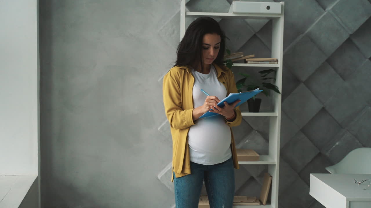 Young pregnant business woman working with documents