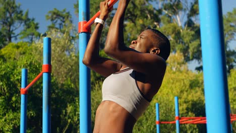 Female-athlete-exercising-pull-up-on-a-pull-up-bar-in-the-park-4k-