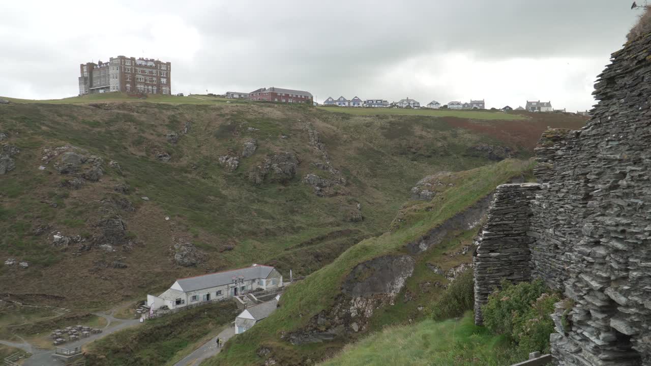 Close up view of one of the Tintagel Castle is a medieval fortification located on the peninsula of Tintagel, Cornwall. View of the Tintagel hotel on the top of the hill opposite the castle ruins
