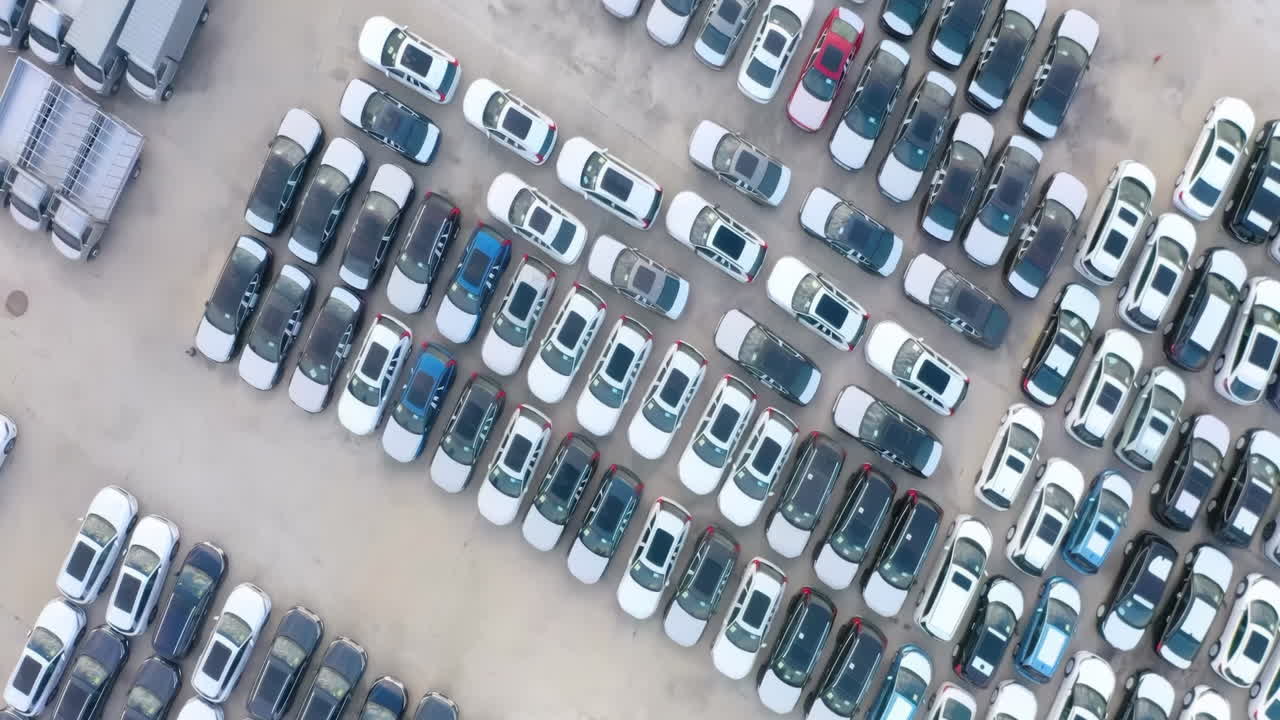 Drone Bird view of Parking lot from above in daytime. There is a lot of cars parked in the parking lot, new car video material produced in car factory